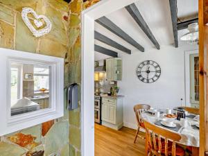 a kitchen and dining room with a table and a clock at 3 Bed in Pwllheli oc-55571 in Nefyn