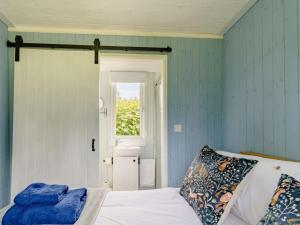 a bedroom with blue walls and a bed and a window at 1 Bed in Kilgetty oc-88421 in Jeffreston