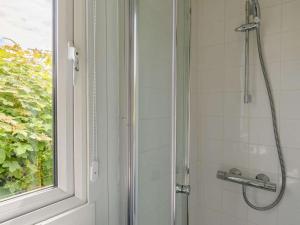 a shower with a glass door next to a window at 1 Bed in Kilgetty oc-88421 in Jeffreston