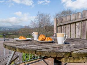 a wooden table with two plates of croissants and two cups at 2 Bed in Bala oc-86963 in Llandderfel