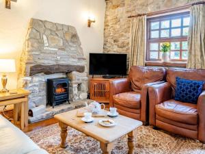 a living room with leather furniture and a stone fireplace at 1 Bed in Swansea oc-77980 in Penclawdd