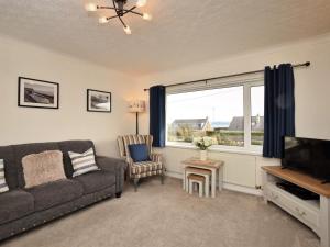 a living room with a couch and a tv and a window at 2 Bed in Moelfre oc-75013 in Moelfre