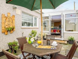 a wooden table with a plate of food and an umbrella at 2 Bed in Moelfre oc-75013 in Moelfre