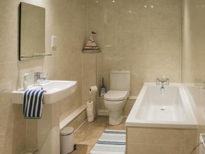 a bathroom with a sink and a tub and a toilet at 2 Bed in Tenby oc-fb284 in Tenby