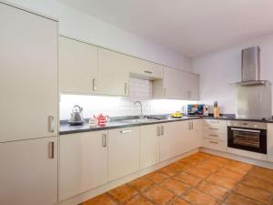 a kitchen with white cabinets and a tile floor at 1 Bed in Corwen oc-52510 in Corwen