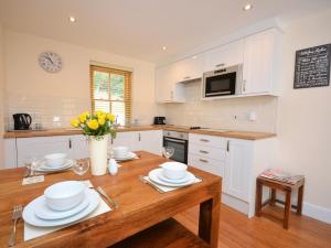 a kitchen with white cabinets and a wooden table at 3 Bed in Narberth oc-36798 in Llawhaden