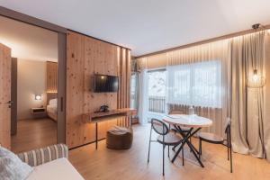 a living room with a table and a bedroom at Kronplatz-Resort Berghotel Zirm in Valdaora