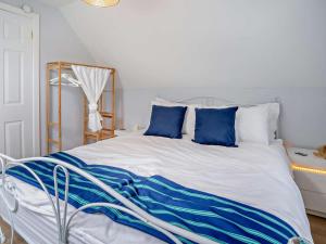 a bed with blue and white sheets and pillows at 2 Bed in Swansea oc-95129 in Penclawdd