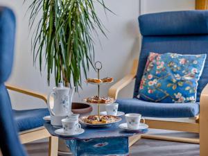 a table with cups and plates of food and a blue chair at 2 Bed in Craven Arms oc-83166 in Clun
