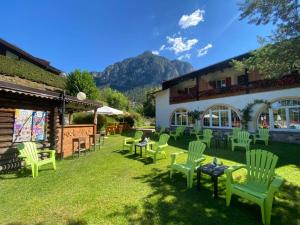 a yard with green chairs and tables and a building at Hotel Rio Bianco in Panchià
