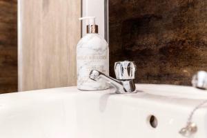 a bottle of soap sitting on a sink in front of a mirror at Modern 3BR Durham Stay for Work Trips in Brandon +10 photos