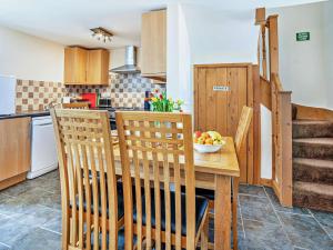 a kitchen with a wooden table with chairs and a bowl of fruit at 1 Bed in Swansea oc-52906 in Llanrhidian +17 photos
