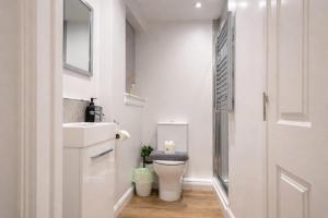 a white bathroom with a toilet and a sink at Roxby a stunning bungalow on the banks of the river within a 2 minute walk of Lake Ullswater and Pooley Bridge in Pooley Bridge