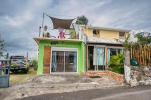 a green and yellow house with a balcony on top at Le Taïbit in Cilaos