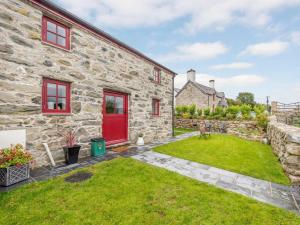a stone house with a red door and a yard at 1 Bed in Llanrwst oc-83950 in Llanrwst