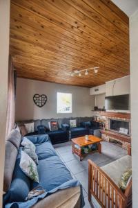 a living room with a blue couch and a wooden ceiling at Le Taïbit in Cilaos