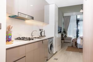 a white kitchen with a sink and a dishwasher at Luxurious Studio Hidden Condo In Dubai in Dubai