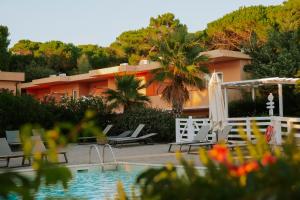 a resort with a pool and chairs and a building at Tuscany Hotel Alle Dune in Marina di Castagneto Carducci