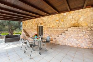 a stone wall with a table and chairs on a patio at Trulli degli Augelli by BarbarHouse in San Michele Salentino
