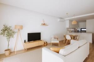 a living room with a white couch and a tv at Casa D'Almo in Almograve