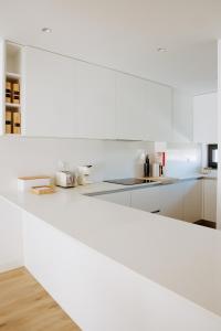 a white kitchen with white cabinets and a counter top at Casa D'Almo in Almograve