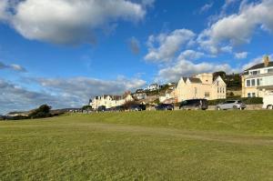 a grassy field with houses and cars parked on it at Cliffside Garden Flat in Woolacombe