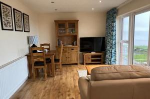 a living room with a couch and a table and a television at Cliffside Garden Flat in Woolacombe +19 photos