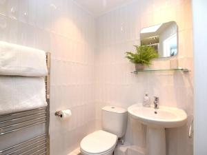 a white bathroom with a toilet and a sink at 3 Bed in Conwy oc-tygos in Llangelynin +14 photos