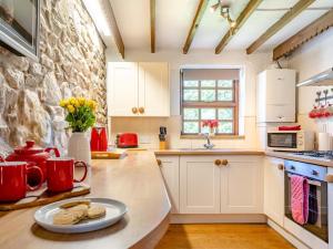 a kitchen with white cabinets and a stone wall at 1 Bed in Swansea oc-77981 in Penclawdd