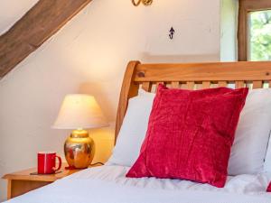 a bed with a red pillow and a lamp on a table at 1 Bed in Swansea oc-77981 in Penclawdd