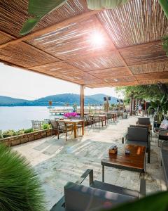 a patio with tables and chairs and a view of the water at Orkide Bodrum in Bodrum City