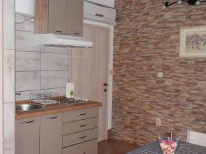 a kitchen with a sink and a brick wall at Guest House Tiho in Silba