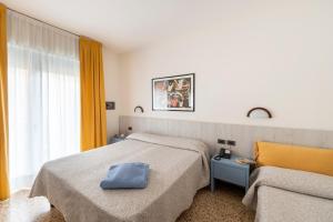 a hotel room with two beds and a chair at Olimpia Hotel & Aparthotel in Bibione