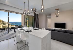 a kitchen and living room with a couch and a table at Aquamarine Luxury Suites - Stegna - Beachfront, Jacuzzi , Smart Home, Great View in Archangelos