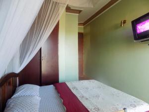 a bedroom with a bed with a tv on the wall at Hotel Shine Sunet in Mbarara
