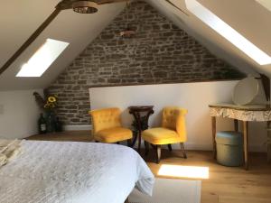 a bedroom with a bed and two yellow chairs at Pinabre Rose Cottage in Plouguenast Langast