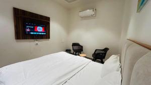 a hospital room with a white bed and two chairs at Hotel Highton in Hānsi