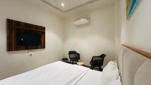 a bedroom with a bed and two chairs and a television at Hotel Highton in Hānsi