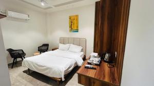 a bedroom with a bed and a wooden table with a table at Hotel Highton in Hānsi