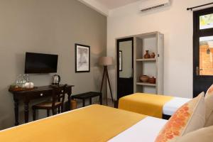 a hotel room with two beds and a desk and a television at Divulgaha Gedara Boutique Hotel in Anuradhapura