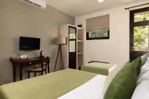 a bedroom with two beds and a desk and a television at Divulgaha Gedara Boutique Hotel in Anuradhapura +26 photos