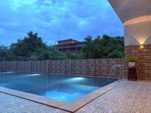 a swimming pool in front of a brick fence at Art cafe in Auroville