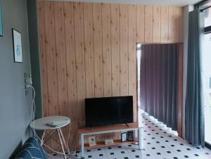 a living room with a flat screen tv on a wooden wall at ฮิมแกนแฟมิลี่เฮ้าส์ in Ban Pong (2)
