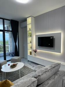 a living room with a couch and a tv on a wall at Sunset Apartment in Orikum