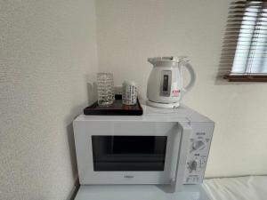 a microwave with a coffee pot on top of it at KIX Nest in Izumi-Sano