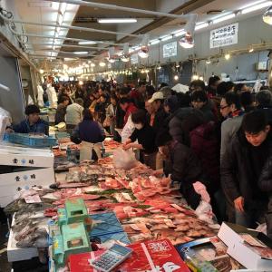 a group of people standing around a table in a market at KIX Nest in Izumi-Sano