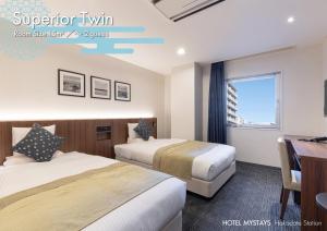 a hotel room with two beds and a desk at HOTEL MYSTAYS Hakodate Station in Hakodate