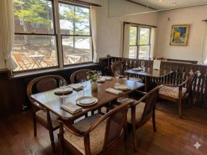 a dining room with tables and chairs and windows at リゾートインブローニュ in Yanaike