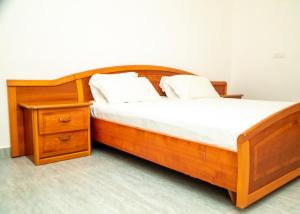 a bed with a wooden frame and a night stand at Résidences Amana in Porto-Novo