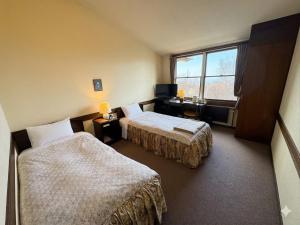 a hotel room with two beds and a window at リゾートインブローニュ in Yanaike